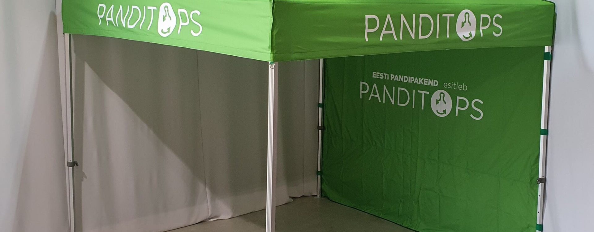 Vihreä PANDITOPS-mainosteltta sisätiloissa, jossa on sivuseinät ja metallinen runko