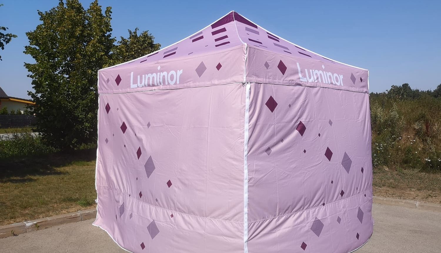 Vaaleanpunainen Luminor teltta ulkona aurinkoisella säällä.