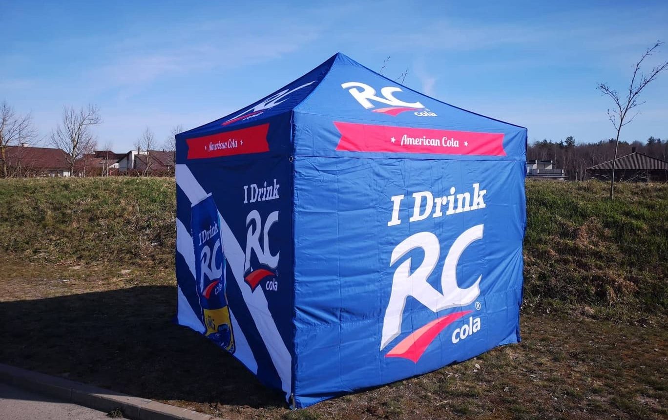 Sininen RC Cola mainostent ulkona pihalla, teksti "I Drink RC" näkyvillä teltan sivuilla